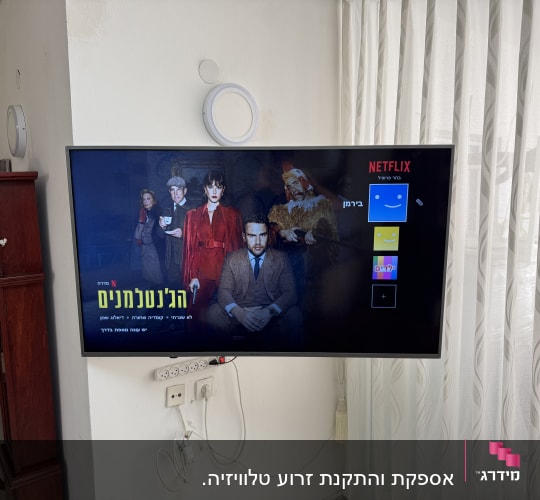 טלוויזיה תלויה על הקיר עם כבלים חשמליים